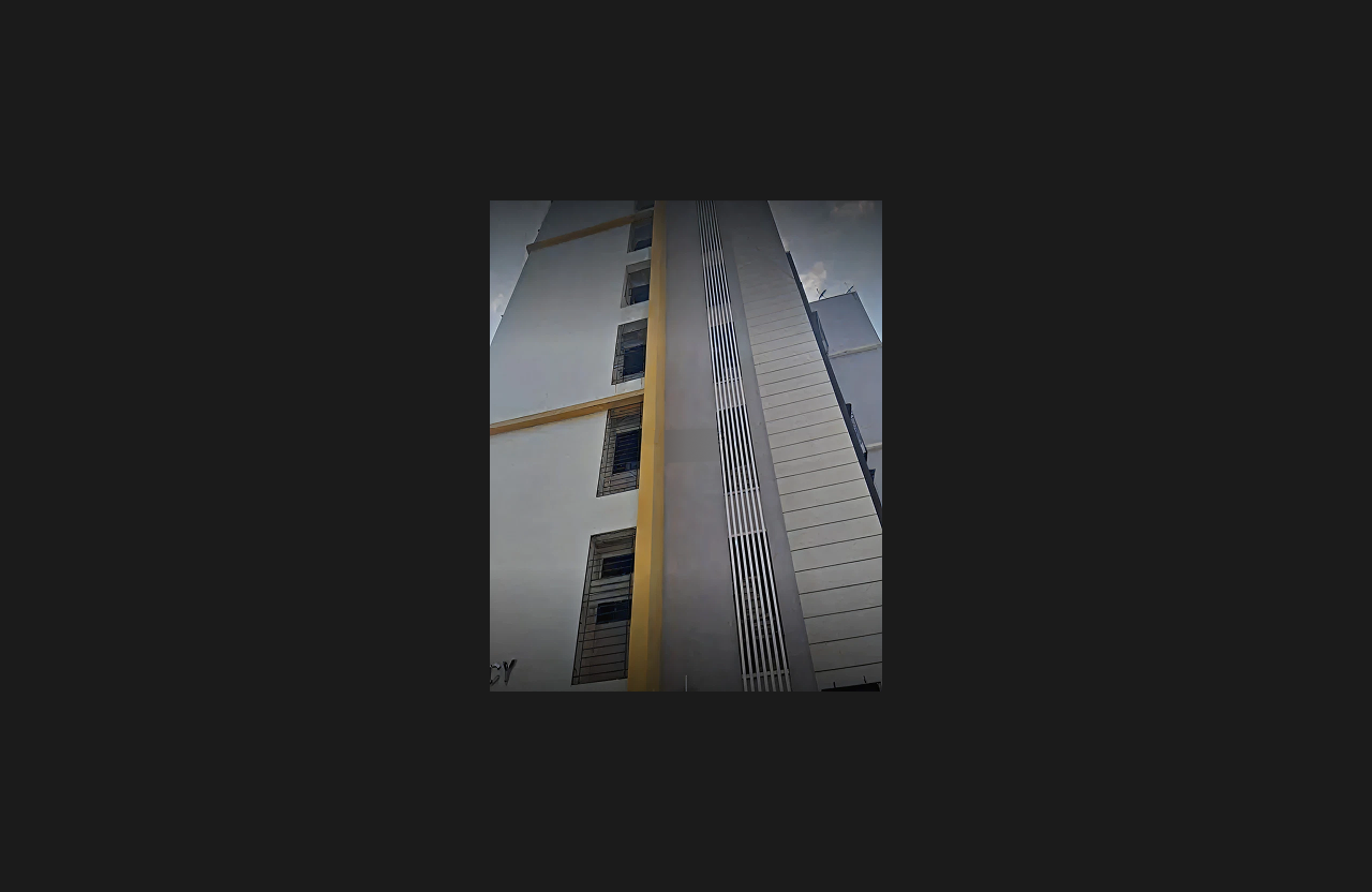 A vertical view of the building façade showing white and grey wall sections with yellow accent lines and vertical grille detailing, highlighting elevation design and window alignment.